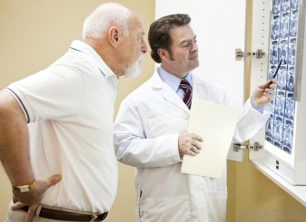 man-with-hands-on-back-looking-at-x-rays-with-doctor[1]